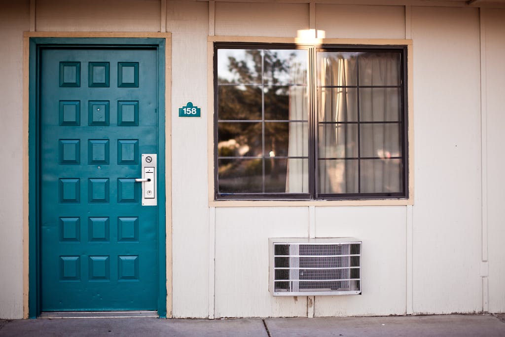 Front view of a teal door and window, typical motel exterior entrance facade.