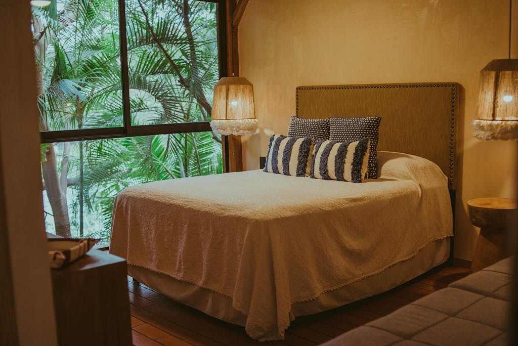 Warm and inviting bedroom with a view of lush greenery, featuring a comfortable bed and stylish decor.